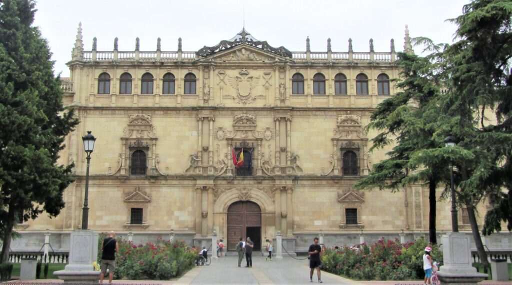 Fachada plateresca del Colegio Mayor de San Ildefonso, en Alcalá de Henares, con jardines de rosales y algunos