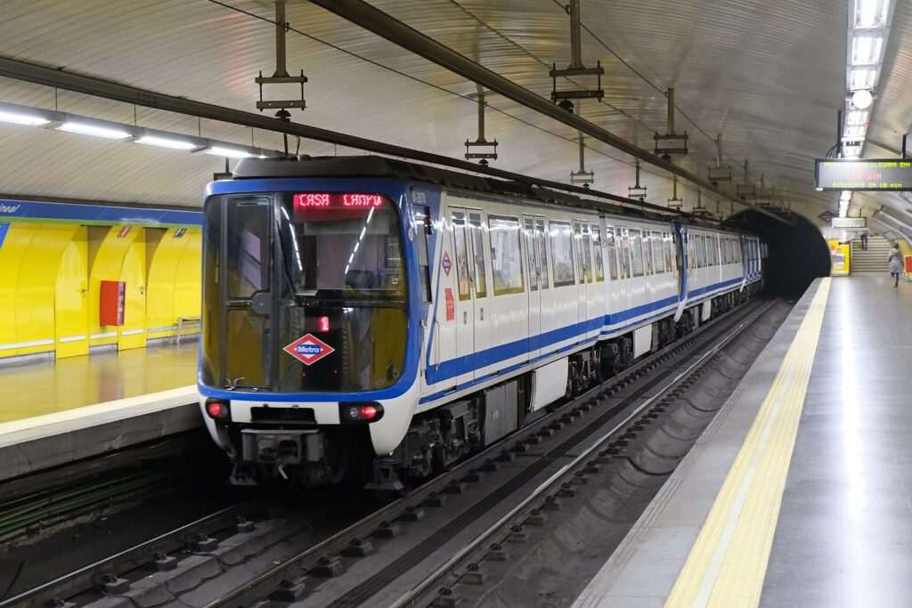 Tren de Metro de Madrid con destino Casa de Campo detenido junto al andén de una estación de paredes amarillas.